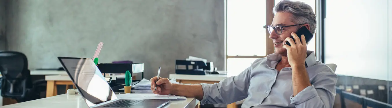 Business owner in a Hawaii office taking a call on a desk phone that is part of a business phone system